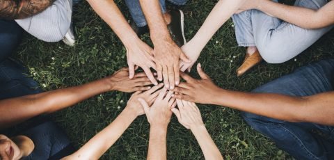 People stacking hands together in the park